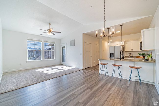 Kitchen featuring vaulted ceiling, stainless steel fridge, open floor plan, a peninsula, and visible vents | Image 4