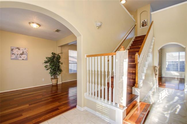This inviting home features a bright entryway with elegant wood and tile flooring, a stylish staircase, and arched doorways that lead to sunlit rooms. Ideal for buyers seeking a charming and spacious interior. | Image 7
