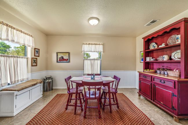 Dining room with visible vents, a wainscoted wall, a textured ceiling, and a healthy amount of sunlight | Image 13