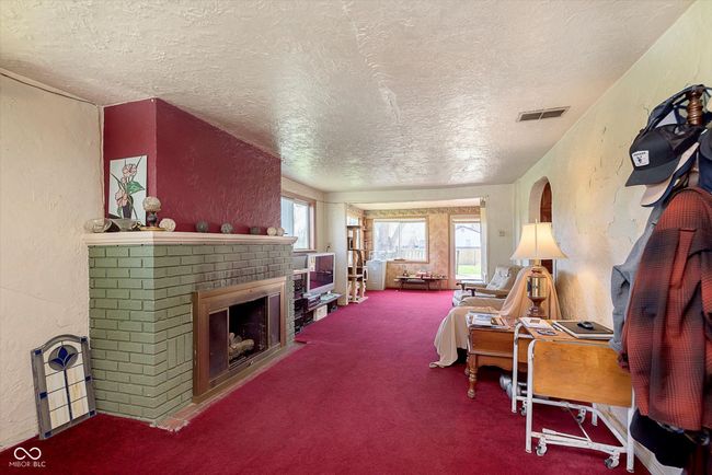 living area with carpet floors, a textured ceiling, a textured wall, and a fireplace | Image 4