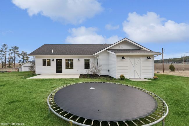 Back of property featuring a patio, a trampoline, a shingled roof, and a lawn | Image 38