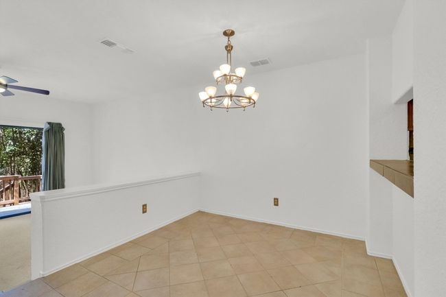 Empty room with ceiling fan with notable chandelier, visible vents, and baseboards | Image 9