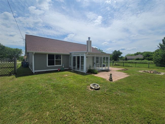 Back of property featuring a fire pit, a sunroom, a patio, and a chimney | Image 22