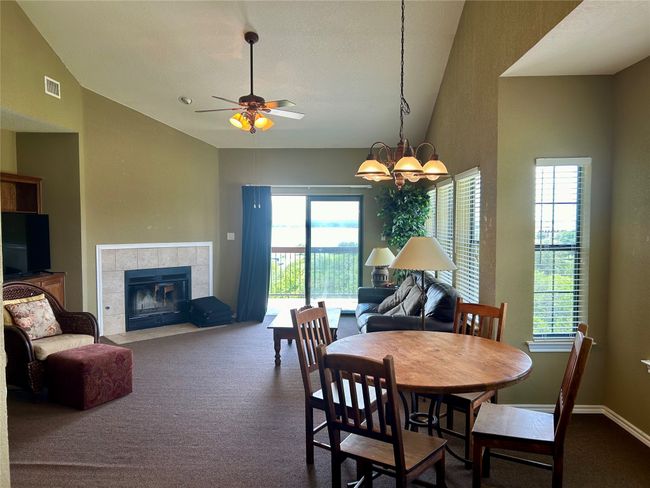 Dining space with lofted ceiling, carpet, ceiling fan, a tiled fireplace, and a chandelier | Image 7
