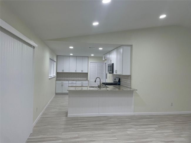 Kitchen featuring appliances with stainless steel finishes, a sink, light wood finished floors, tasteful backsplash, and white cabinetry | Image 17