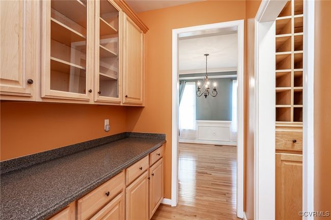 Kitchen featuring light brown cabinetry, light wood-type flooring, a wainscoted wall, a chandelier, and a decorative wall | Image 7