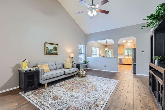 Living room featuring high vaulted ceiling, ceiling fan, wood finished floors, and arched walkways | Image 6