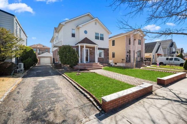 View of front facade featuring driveway, an outdoor structure, a front lawn, a garage, and brick siding | Image 23