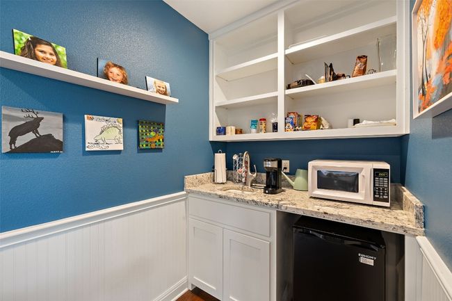 Bar featuring a sink, white microwave, wainscoting, and refrigerator | Image 28