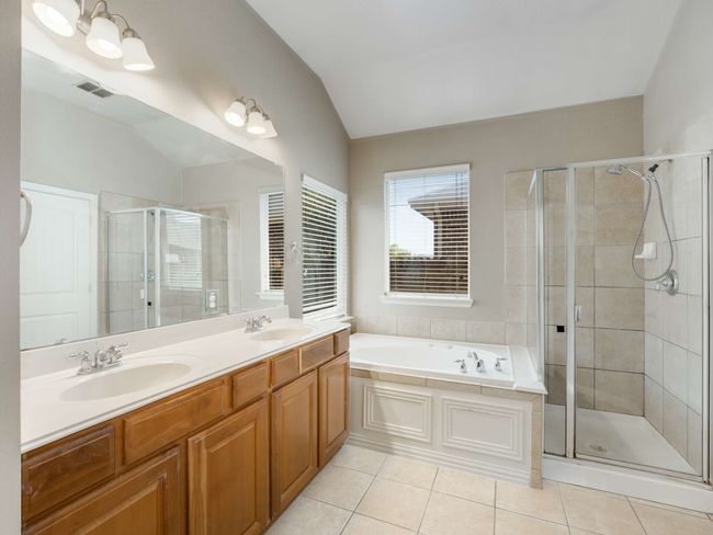 Bathroom featuring vaulted ceiling, a shower stall, a garden tub, tile patterned flooring, and double vanity | Image 17
