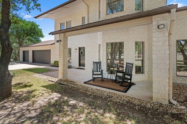 Back of house with a garage, covered porch, stone siding, and concrete driveway | Image 5