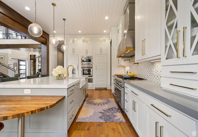 Kitchen featuring a sink, wall chimney range hood, appliances with stainless steel finishes, butcher block counters, and hardwood / wood-style floors | Image 27