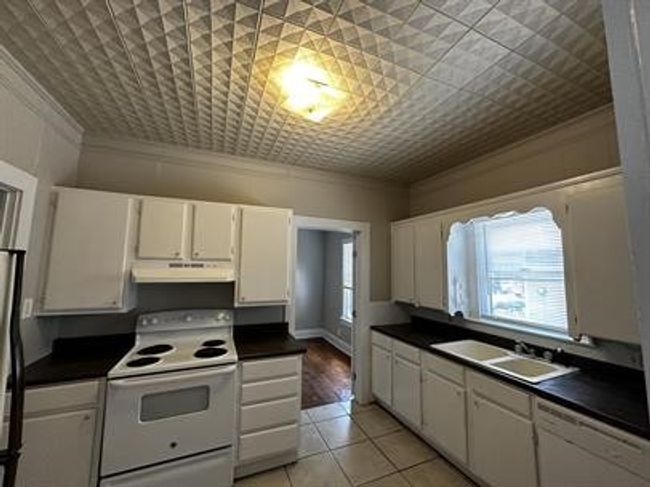 Kitchen featuring white range with electric stovetop, crown molding, under cabinet range hood, dark countertops, and dishwasher | Image 6