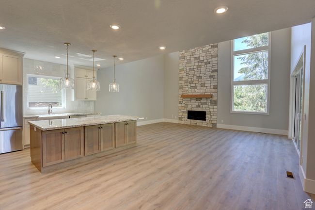 Kitchen featuring stainless steel refrigerator, a kitchen island, light wood-style flooring, tasteful backsplash, and recessed lighting | Image 5