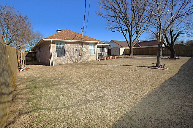 Rear view of property with a yard, brick siding, a fenced backyard, and a shingled roof | Image 38