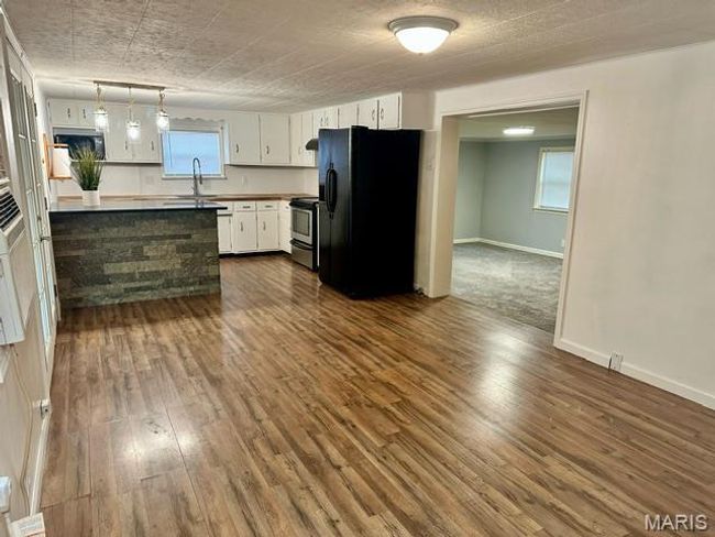 Kitchen with white cabinetry, black fridge, and hanging light fixtures | Image 17