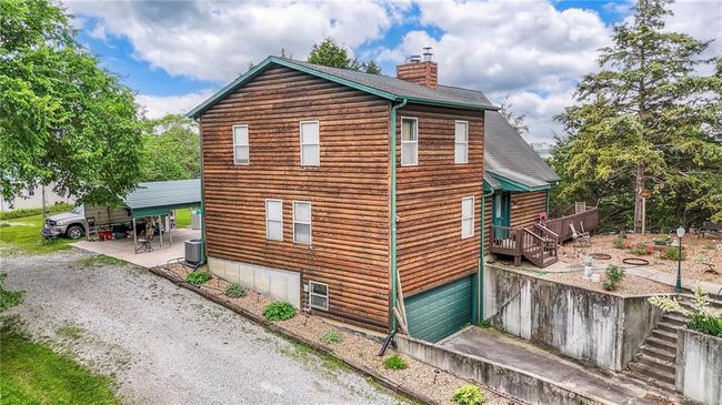 View of side of home featuring a chimney, an attached garage, driveway, and a shingled roof | Image 58