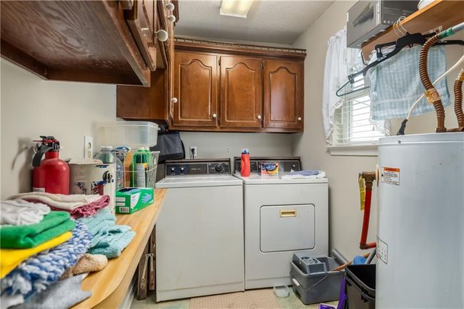 Laundry room featuring cabinet space, washing machine and dryer, and water heater | Image 22
