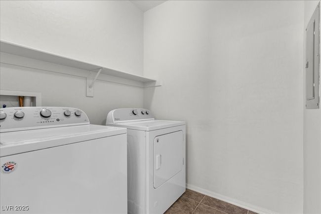 Laundry room featuring washing machine and dryer, electric panel, and dark tile patterned floors | Image 32