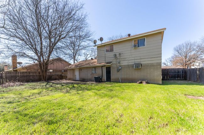 Back of house with a yard, a fenced backyard, brick siding, and a wall mounted air conditioner | Image 15