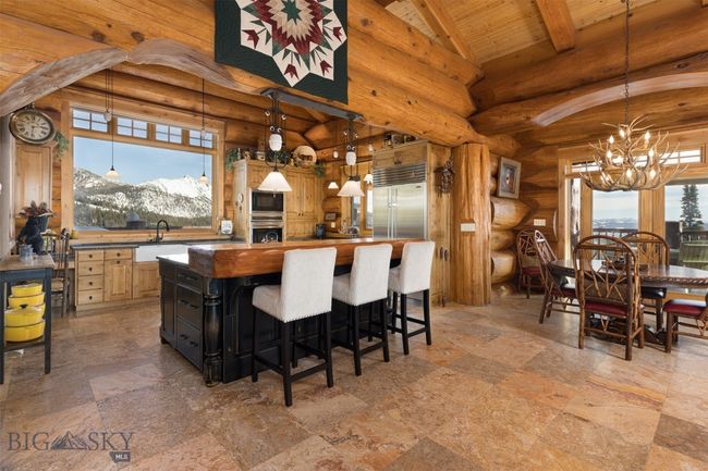 Main level kitchen with arched entry, kitchen island/seating, mountain views, wooden slab counter and built-in appliances. | Image 29