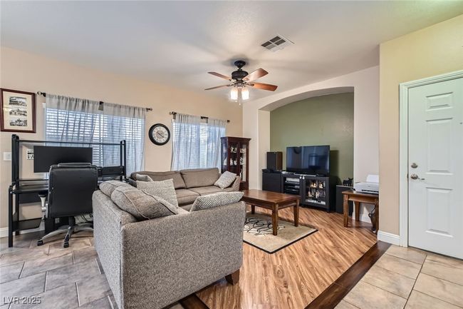 Living room area showing the entertainment center area, windows and beautiful tile and wood flooring just off the front entryway | Image 7