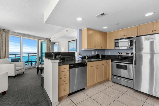 Kitchen with light brown cabinetry, a sink, visible vents, and stainless steel appliances | Image 13