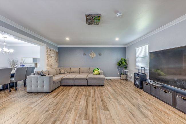 Living area with light wood-style floors, a chandelier, ornamental molding, and recessed lighting | Image 9