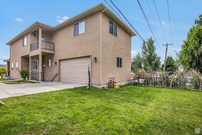 View of side of home with an attached garage, stucco siding, concrete driveway, and a yard | Image 26