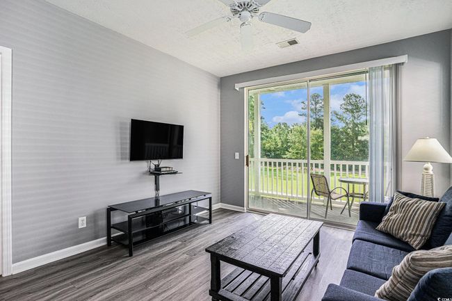 Living area with wood finished floors, ceiling fan, and a textured ceiling | Image 4