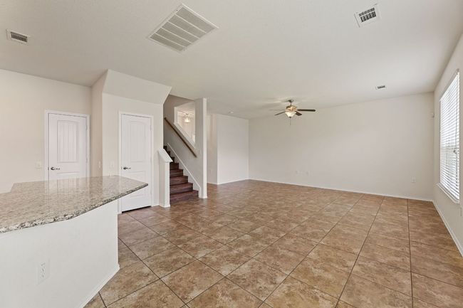 Unfurnished living room featuring stairway and ceiling fan | Image 6