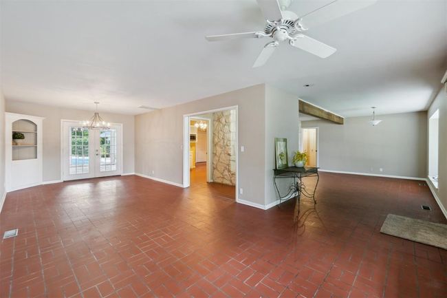 Unfurnished living room featuring brick flooring, ceiling fan, and a chandelier | Image 5
