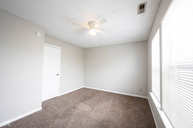 empty room featuring carpet, visible vents, a ceiling fan, baseboards, and a textured ceiling | Image 24