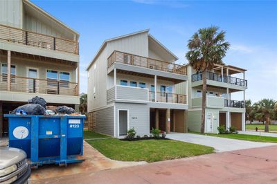 Multi-story home featuring a gray exterior with black trim and balconies, offering a spacious car ports and a fresh coastal vibe. | Image 3