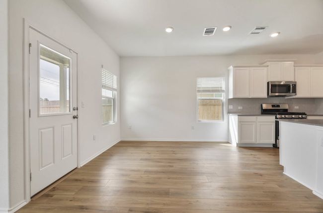 Kitchen featuring appliances with stainless steel finishes, decorative backsplash, white cabinetry, light wood-style floors, and recessed lighting | Image 18
