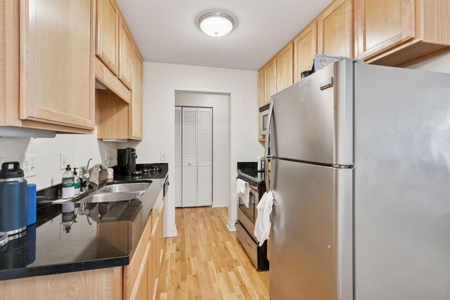 Efficient galley-style kitchen with granite countertops, stainless steel appliances, and hardwood floors—smart design meets modern style just steps from Lake Bde Maka Ska. | Image 4