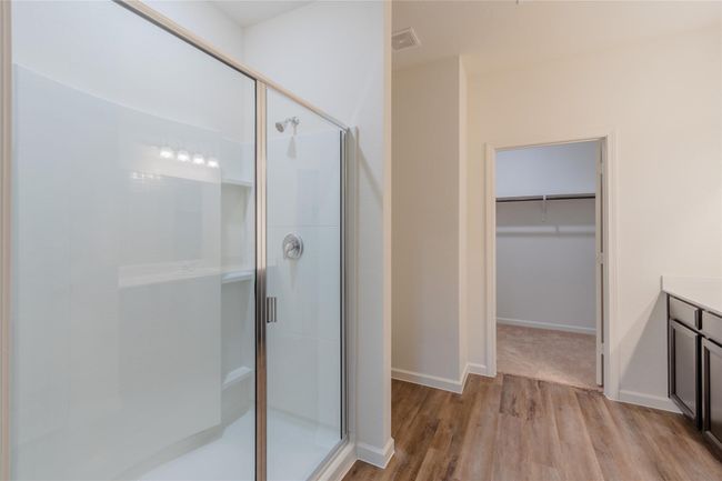 Full bath featuring a shower stall, wood finished floors, a spacious closet, and baseboards | Image 14