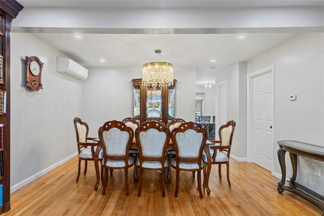Dining area featuring an AC wall unit, baseboards, a chandelier, and light wood-style flooring | Image 5