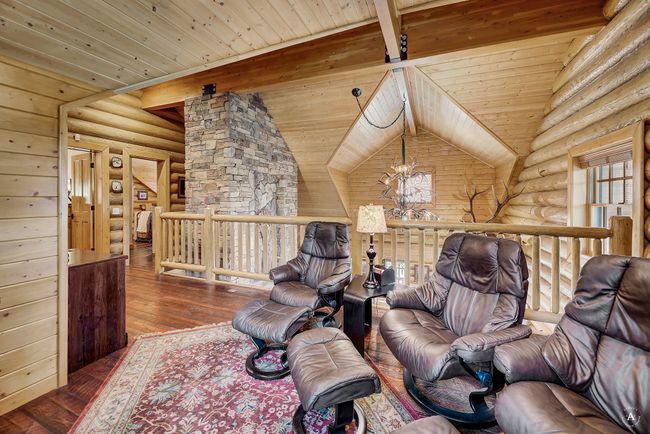 Living room featuring log walls, a wooden ceiling with exposed beams, wood-type flooring, and a chandelier | Image 32