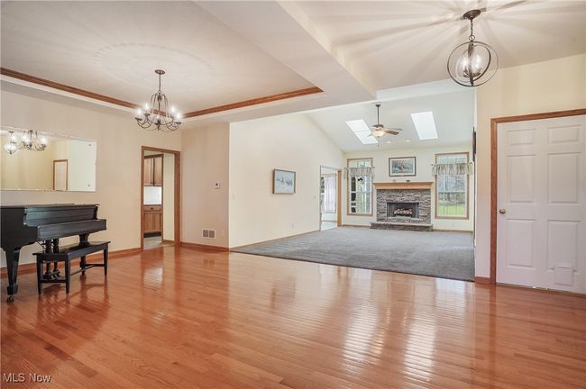 Living room featuring light wood-type flooring, visible vents, baseboards, and a notable chandelier | Image 10