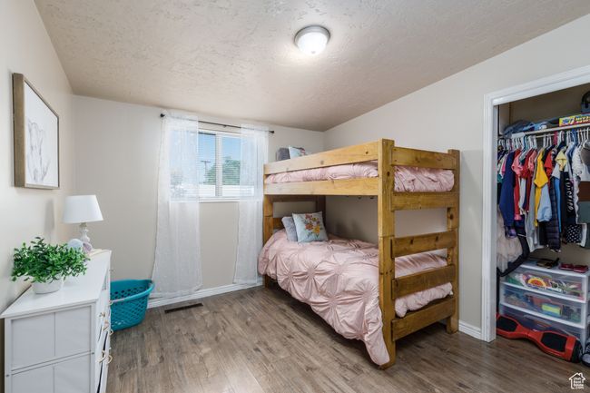 Bedroom with a textured ceiling, wood finished floors, and a closet | Image 13