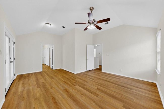 Unfurnished bedroom featuring lofted ceiling, light wood-style flooring, baseboards, and a ceiling fan | Image 17