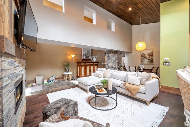 Living area featuring a fireplace, baseboards, a towering ceiling, wood ceiling, and wood finished floors | Image 7
