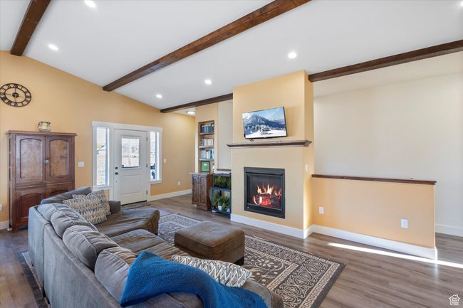 Living area featuring wood finished floors, baseboards, lofted ceiling with beams, recessed lighting, and a glass covered fireplace | Image 15