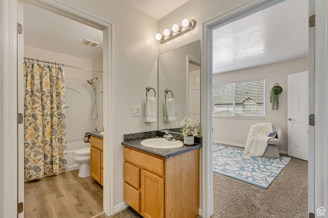 Bathroom with vanity, toilet, visible vents, shower / bath combo with shower curtain, and wood finished floors | Image 13
