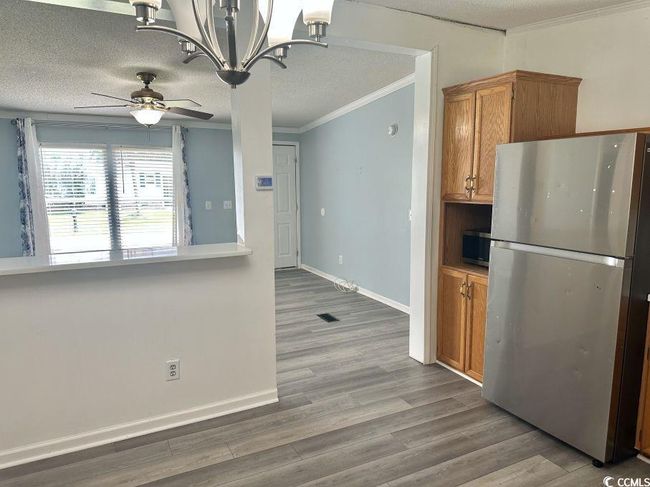 Kitchen featuring appliances with stainless steel finishes, crown molding, ceiling fan, wood finished floors, and brown cabinetry | Image 9