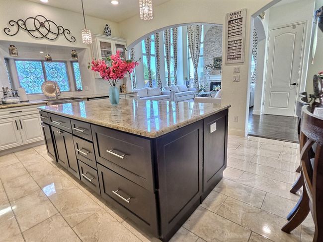 Kitchen with a sink, arched walkways, light stone countertops, white cabinets, and recessed lighting | Image 13