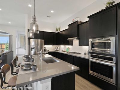 Kitchen featuring appliances with stainless steel finishes, light hardwood / wood-style flooring, sink, decorative backsplash, and an island with sink | Image 3