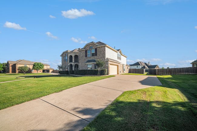 View of front facade with brick siding, an attached garage, and driveway | Image 4