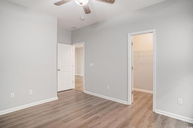 Unfurnished bedroom featuring light wood-type flooring, a spacious closet, a closet, and ceiling fan | Image 22